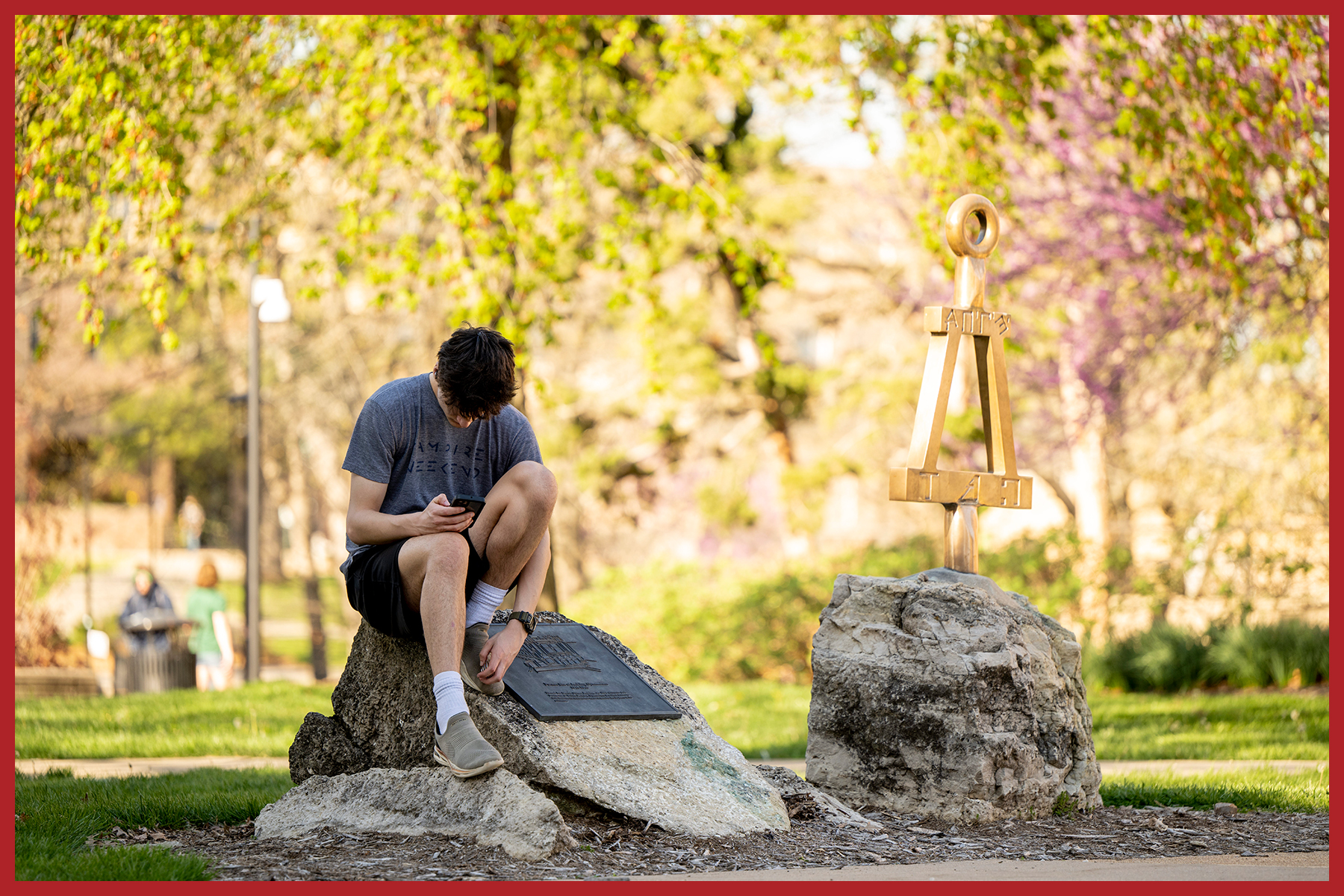 student sitting on rock looking at phone